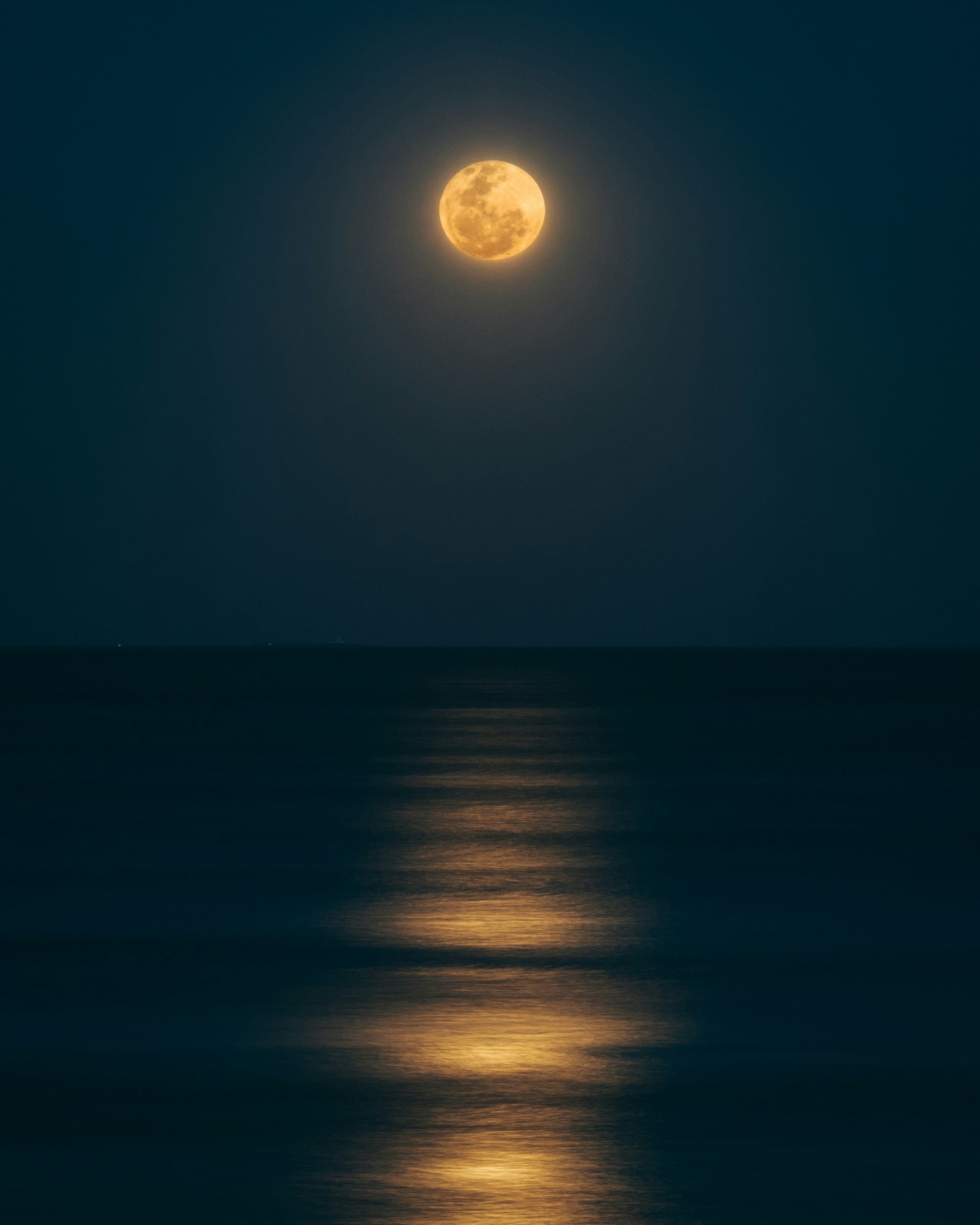 夜の水面にうかぶ月とその光の帯