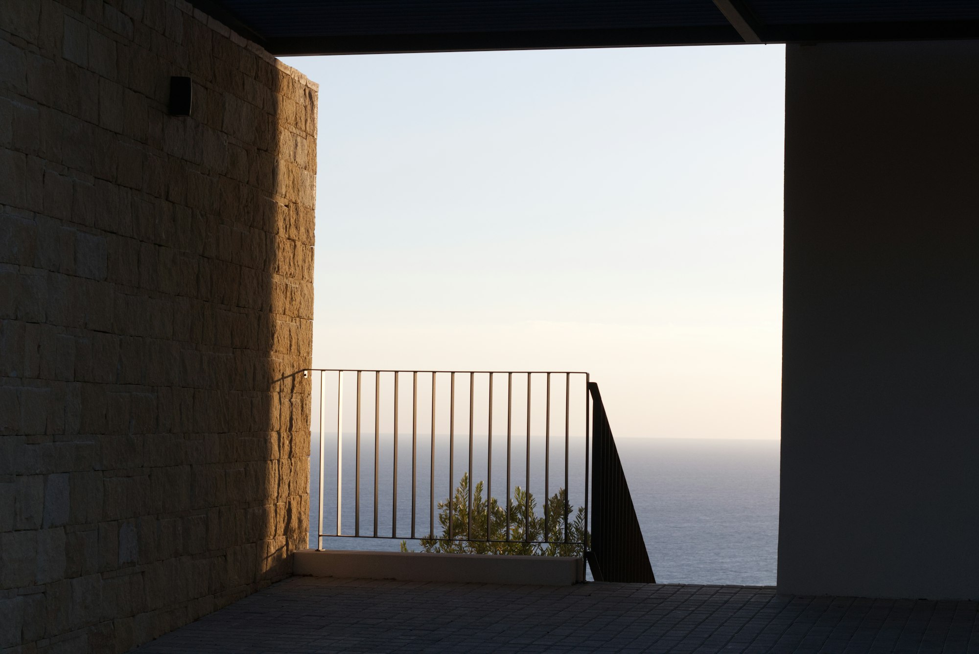 瀬戸内の海を見下ろす丘に建つ、白い箱型のミニマル建築。夕暮れの光